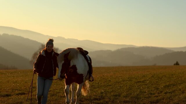 Young woman gently cuddling and interacting with her pinto Haflinger mix mare, emotional bond and trust at sunset