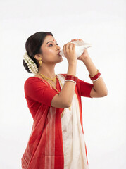 young fair skinned bengali woman playing shankh during durga puja ritual isolated on white background representing devotion culture and tradition