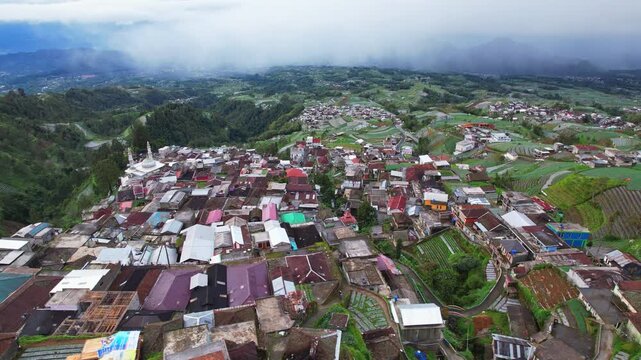 Aerial drone footage on top of the famous Nepal Van Java village, on the slope of Sumbing volcano, in Magelang area, Java island, Indonesia, in a cloudy mood, and many vegetable fields 