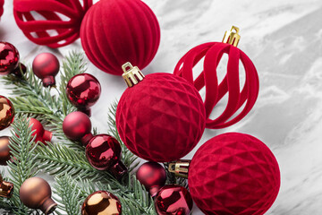 Red velvet baubles, Christmas ball ornaments and pine branches on marble table background