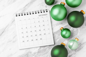 December calendar with green christmas ball decoration on marble table background