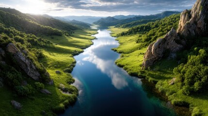 Obraz premium A breathtaking view of a river gracefully winding through a lush green valley, offering a serene and idyllic scene, ideal for nature lovers and landscape photography.