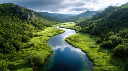 Fototapeta premium This serene image features a winding river flowing through a lush, green valley, capturing the essence of harmony and tranquility in nature’s untouched landscapes.