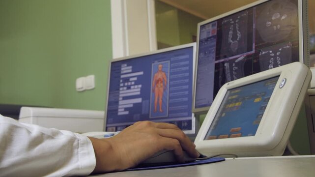 A radiology technician works on a computer with CT scans of the skull in a hospital