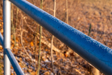 Frost-covered railing glimmers under the soft morning light in a quiet, wintry landscape