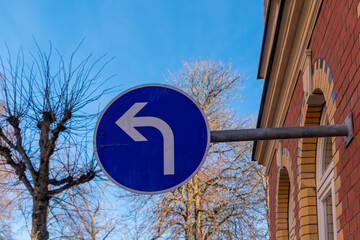 Turning left in a vibrant townscape under a clear blue sky with trees standing tall