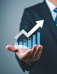 Businessman holding a glowing bar chart with an upward trend arrow, symbolizing business growth and financial success.