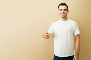 Man smiling, pointing at blank white t-shirt, showing product, advertising casual apparel