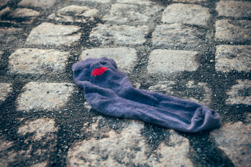 Lost sock resting on cobblestones, a reminder of a forgotten journey in a quiet street