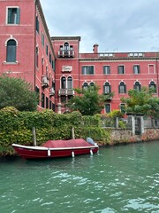 Red Historic Building Along Venetian Canal.
Traditional red building with green shutters beside canal in Venice, Italy, calm water and classic