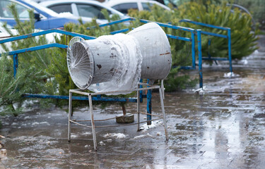 Manual Christmas tree netting funnel on a wet city sidewalk during a winter holiday market.