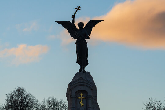 Tallinn, Estonia - December 28, 2025: Silhouette of the Russalka Memorial angel holding an orthodox cross against a sunset sky.