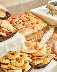 A diverse buffet features savory focaccia and various fresh baked goods.