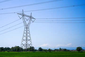 Extra High Voltage Air Line or in Indonesia it called SUTET. High voltage electricity pole with farmland and blue sky in the background.