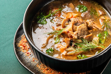 A rich, hearty mushroom soup with carrots and fresh dill/parsley is presented in a dark bowl on a textured plate, ready to eat