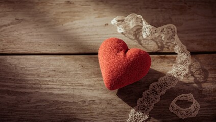 Fabric heart resting on wooden surface, suitable for layout or editorial header backgrounds