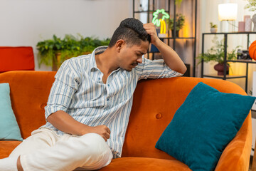 Indian man at home looks down after hard day feels tired low mood with stress and fatigue asks for...