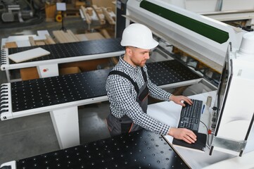 Carpenter operating cnc machine in furniture factory