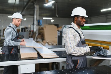 Furniture factory workers operating cnc machine for sofa production