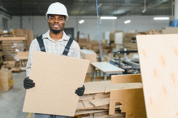Skilled worker holding wood panel in factory setting