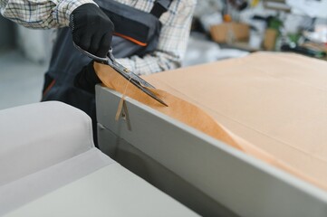 African american Furniture maker cutting packing paper with scissors in a furniture factory