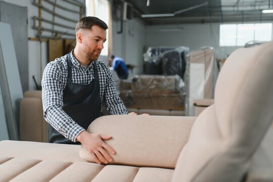 Carpenter upholstering sofa in furniture factory