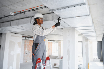 Construction worker installing ventilation system on building site