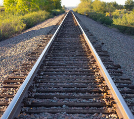 Fototapeta premium horizontal image of railroad tracks leading off into the distance with shiny metal tracks with rocks in the middle empty space for type on either side and in the middle background backdrop or wallpape