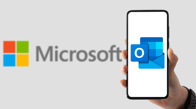 Hand holding smartphone with Microsoft Outlook app on screen