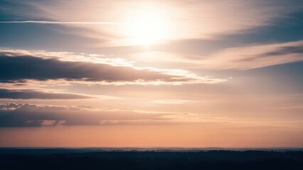 Fototapeta premium Sun shines through clouds above distant trees, casting orange and blue tones