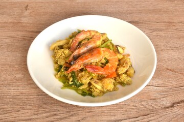stir fried shrimp and squid in yellow curry couple egg on plate