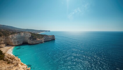 Fototapeta premium Turquoise waters and rugged cliffs along a scenic coast with distant resorts, suitable for layout backgrounds