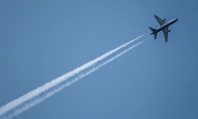 A jet streaks across a clear blue sky, leaving a vapour trail behind