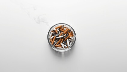 Overhead shot of a cigarette butts-filled ashtray on a white surface, highlighting smoking-related health concerns and lifestyle choices