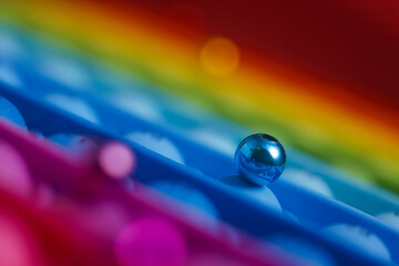 Small ball on a rainbow background. Rainbow background. Macro view of little blue ball on rainbow background