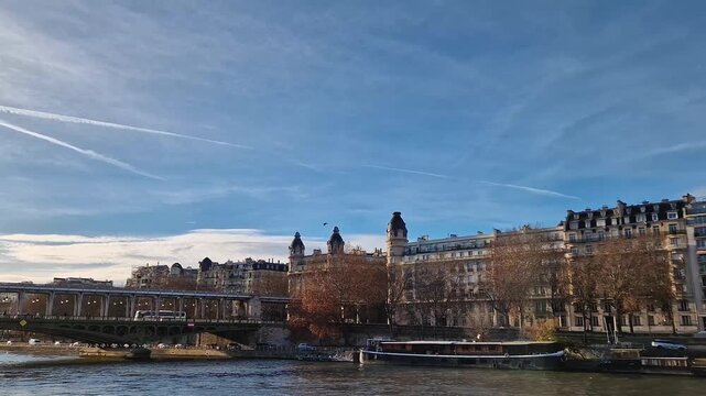 A serene view along the Seine in Paris with the Bir-Hakeim Bridge, elegant Haussmann style apartments, and autumn trees under bright blue sky, showcasing the city timeless architectural beauty