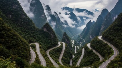 Serpentine road winds through towering, green mountain peaks, partially shrouded in mist