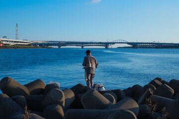 堤防で釣りをする老人、テトラポットの上での釣り