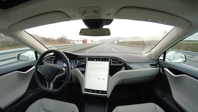Self-driving fully autonomous Tesla driverless car driving by itself on highway