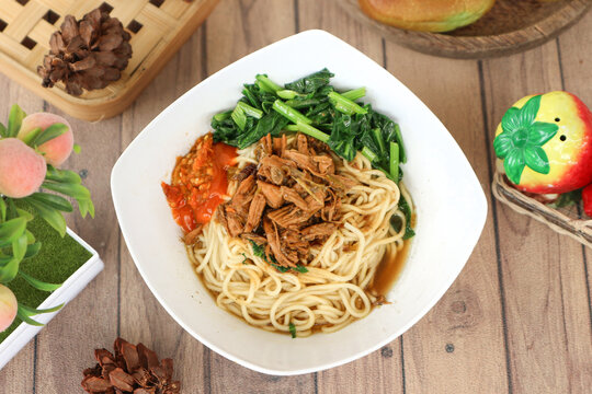 A bowl of Indonesian mie ayam (chicken noodle), consists of Chinese egg noodles, stir-fried diced chicken with sweet soy sauce (ayam kecap), boiled green caisim, and lots of bird's eye chili paste.
