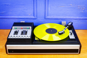 Vintage turntable vinyl record player with yellow vinyl on a table