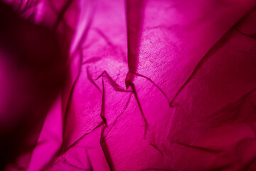 Extreme close up of red empty plastic bag background. The plastic surface is wrinkly and tattered making abstract pattern. Selective focus, shallow depth of field.