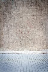 Gray lined stucco street wall and a pavement