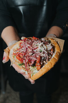 Man holding kebab in bread on a plain background