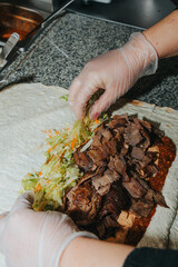 The process of preparing shawarma kebab. Chef's hands. Sauces, vegetables, meat