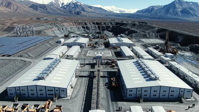Aerial view of a remote mining exploration camp with modular buildings and solar panels, Harsh mountainous terrain provides a dramatic backdrop for the industrial facility