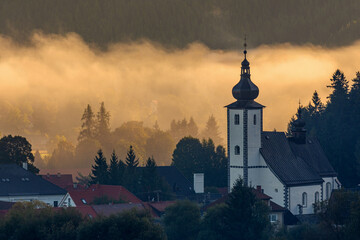 Ancient Slovakian church in village shrouded in golden fog.