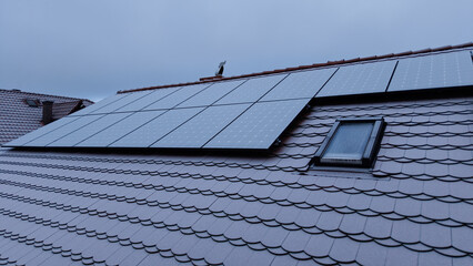Drone view of solar panels on a rooftop during morning frost, with photovoltaic panels covered in frost or light snow.