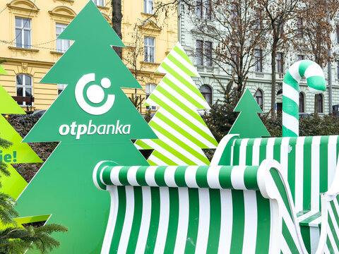 Zagreb, Croatia - December 14, 2025: Green and white striped sleigh with OTP banka logo surrounded by festive trees, creating a cheerful holiday atmosphere in the city