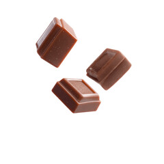 Three chocolate squares, in mid-air, a dark background.  Glossy, rich brown chocolate, showing a slightly rough texture